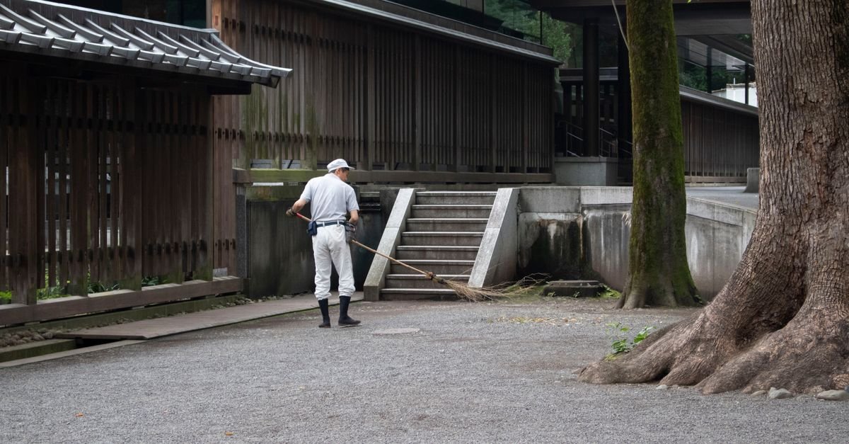 A man sweeping an outdoor paved area, the routine maintenance a sealed slab mostly needs
