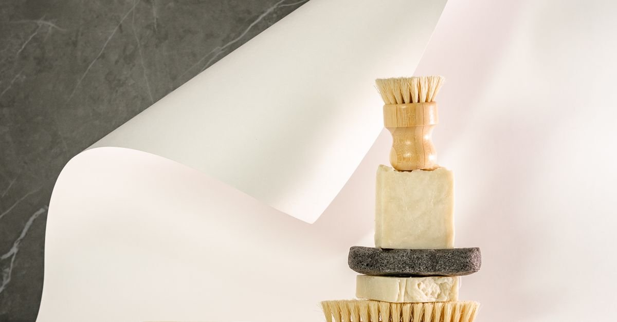 Eco-labelled cleaning tools and bars of soap arranged in neutral tones on a pale surface