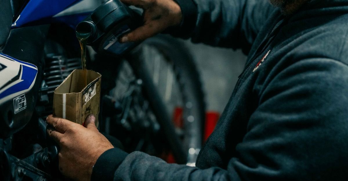 Mechanic pouring fresh oil into a small engine during routine maintenance