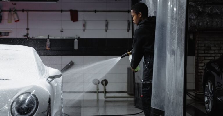 Pressure washer wand in use, rinsing foam from a vehicle in a garage bay