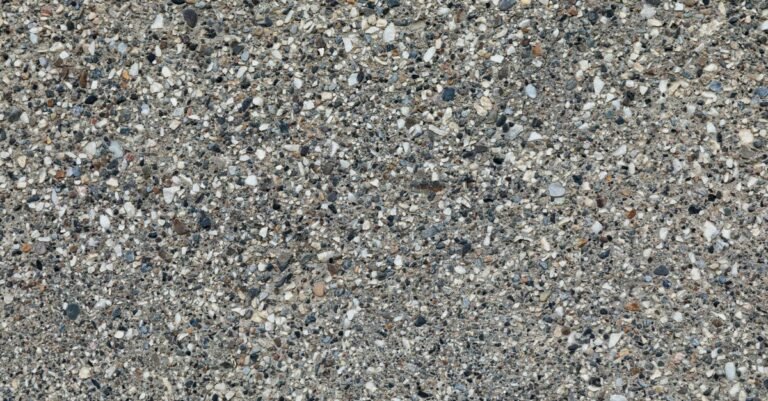 Rough grey concrete surface with rounded pebbles standing out of the cement paste around them