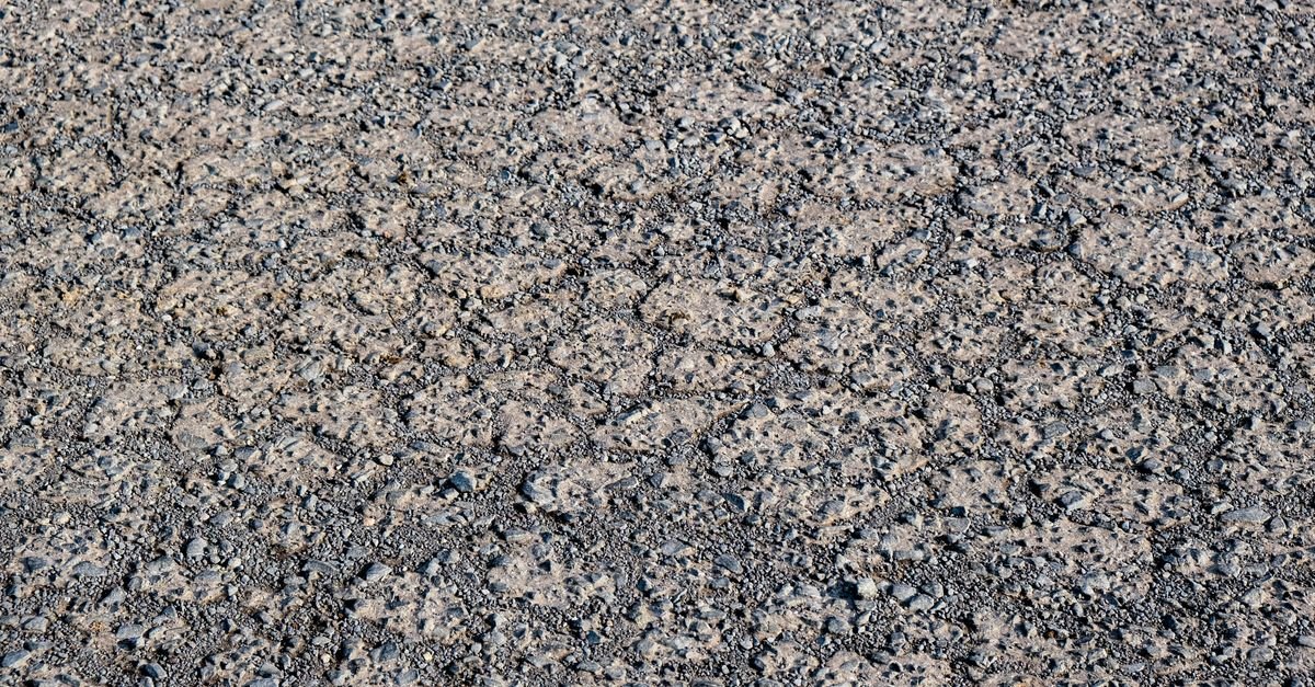 Rough textured cement pavement with small embedded stones and fine surface cracking