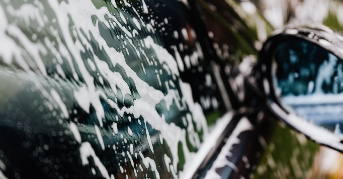 Thick detergent foam clinging to a car panel