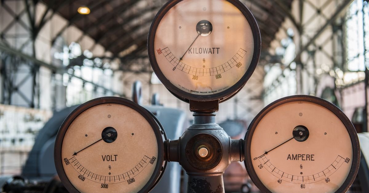 Close-up of vintage kilowatt, volt and ampere gauges on an industrial panel, the three quantities a generator specification is built from
