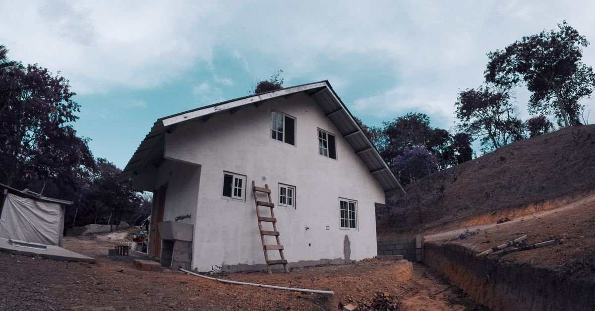 An extension ladder leaning against a house exterior beside the roofline