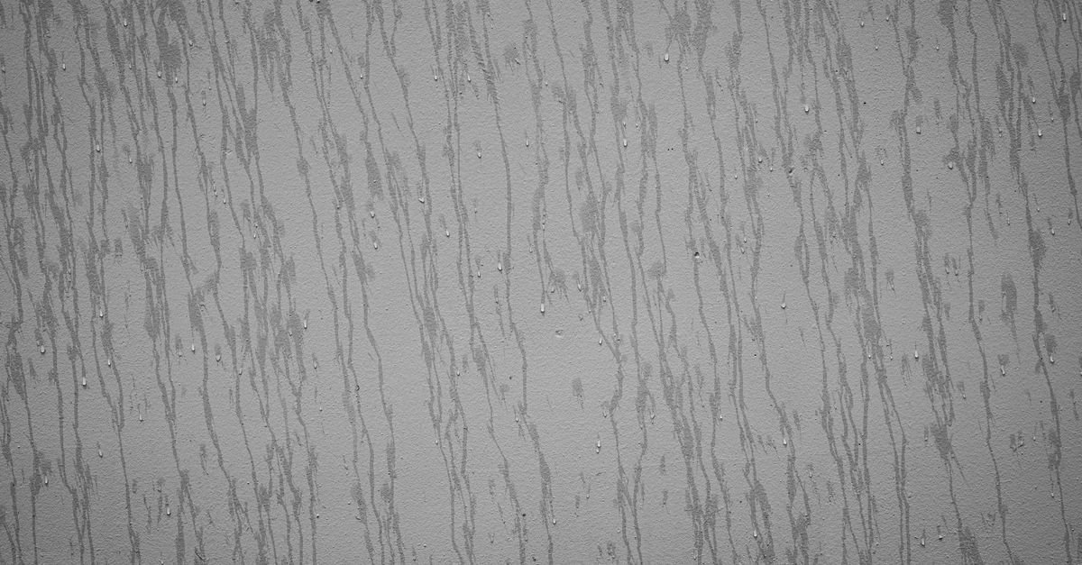 Dark vertical rain streaking running down a pale painted exterior surface