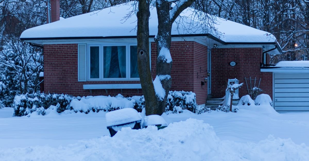 A suburban house under fresh snow on a still winter morning after the first hard freeze