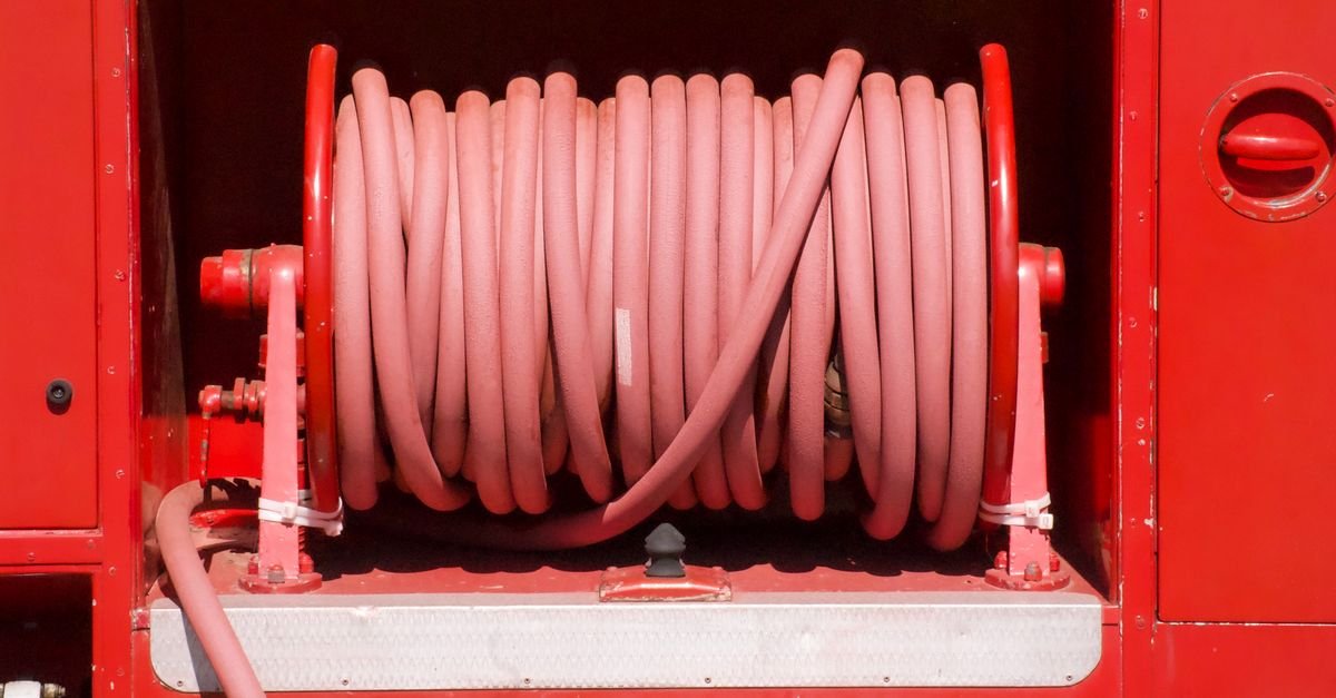 Hose wound in flat, even wraps on an open drum reel mounted to a vehicle