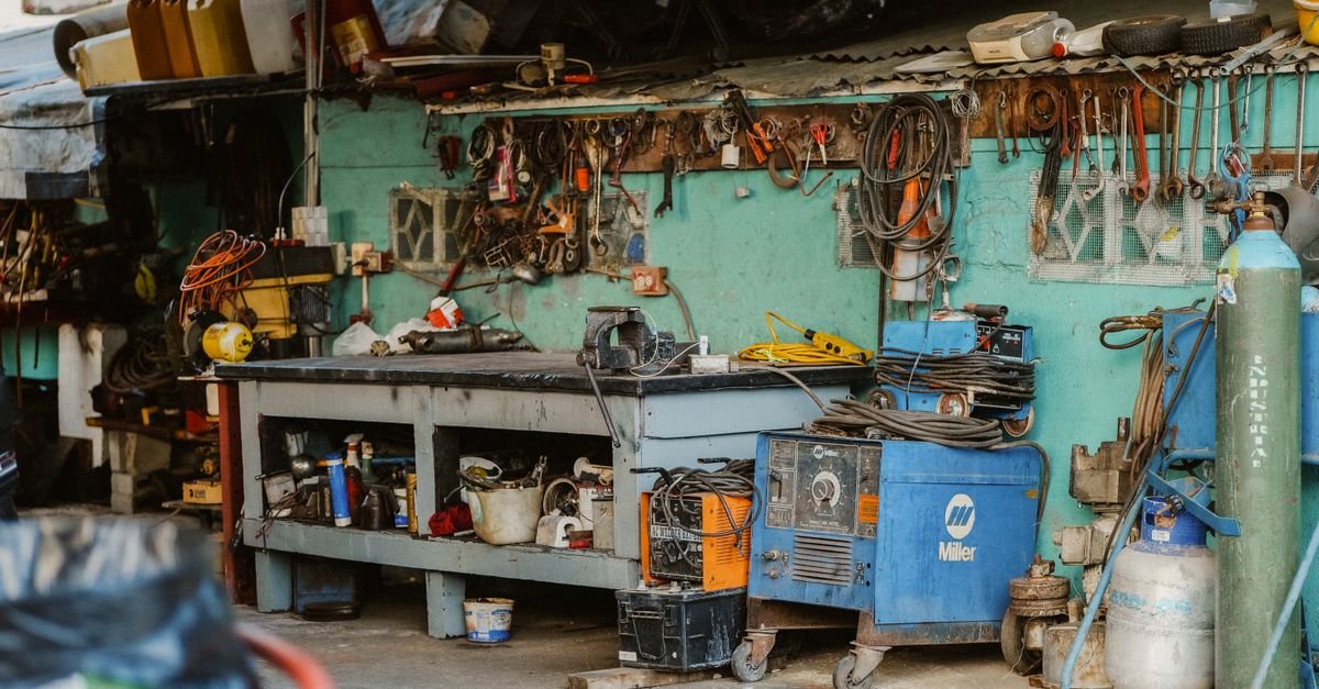 A workshop wall crowded with tools and storage where a hose reel has to compete for mounting space