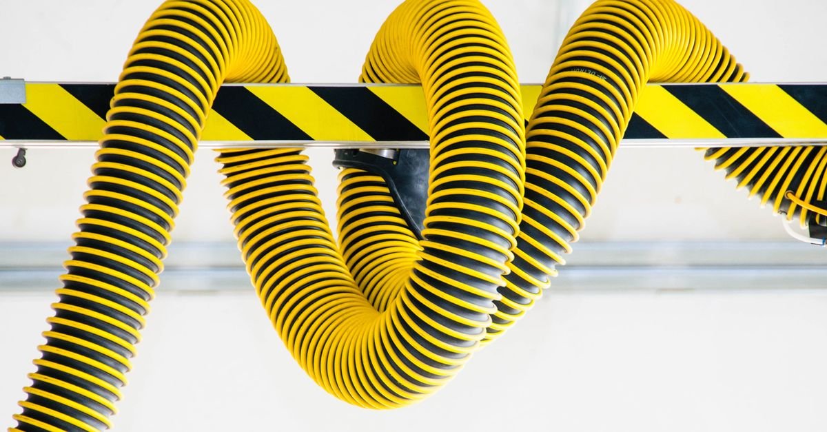 Yellow high-pressure hoses coiled tightly around a metal beam, wrap pressed against wrap