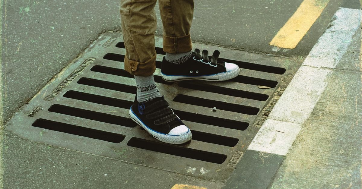 Steel storm drain grating set into the asphalt at the edge of a street