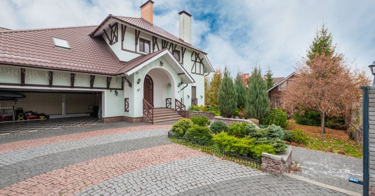 Brick block paved driveway curving past a suburban house and front garden