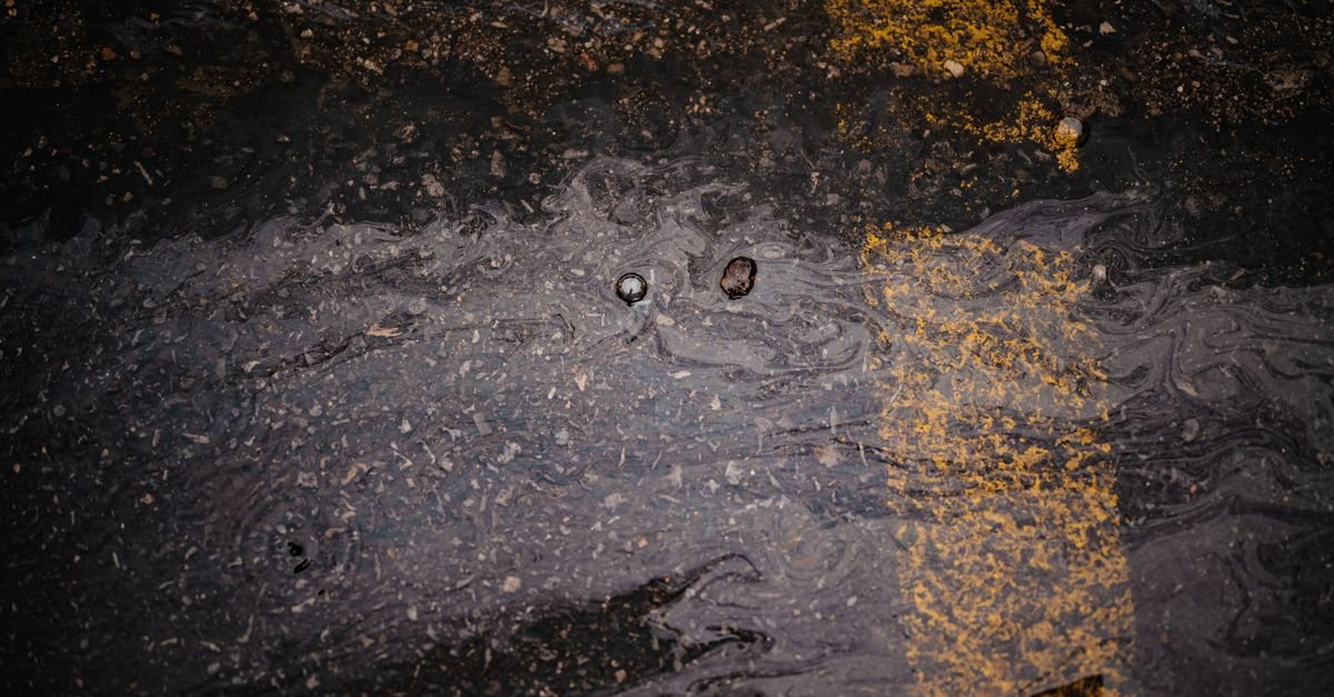 Wet black asphalt surface with a painted yellow line running across it