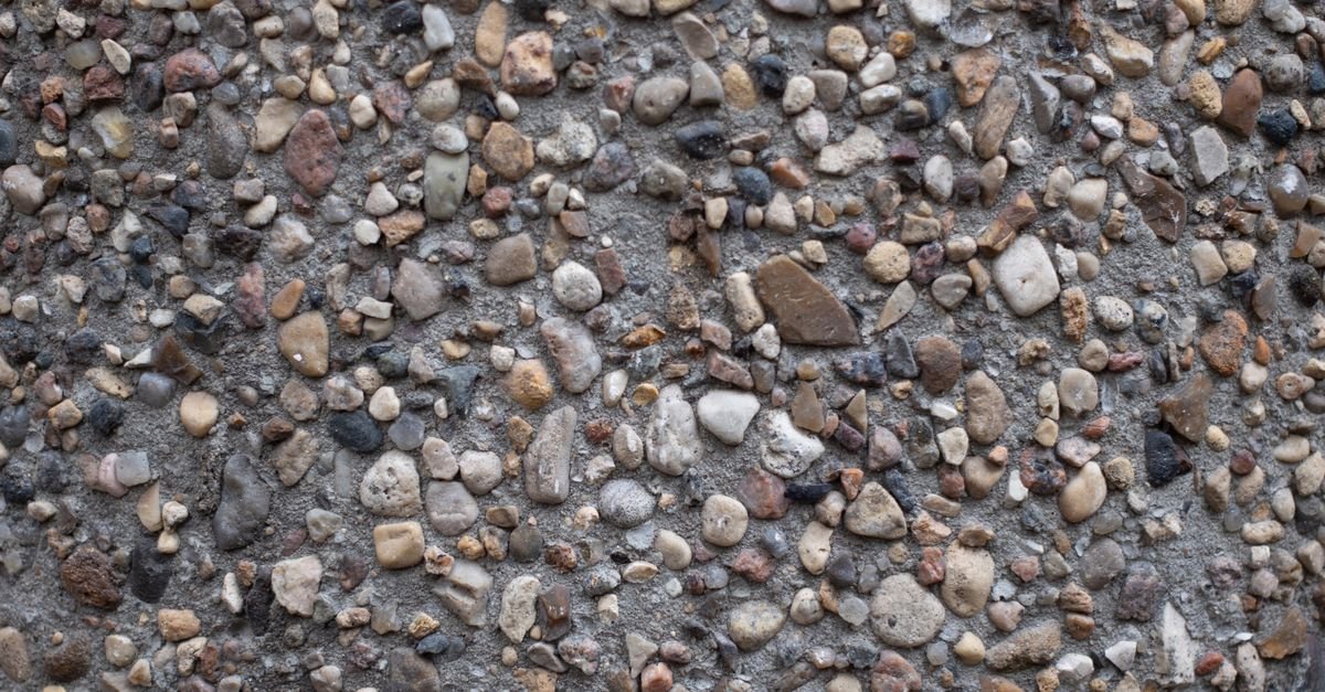 Close-up of exposed-aggregate concrete showing embedded stones that can loosen under high pressure