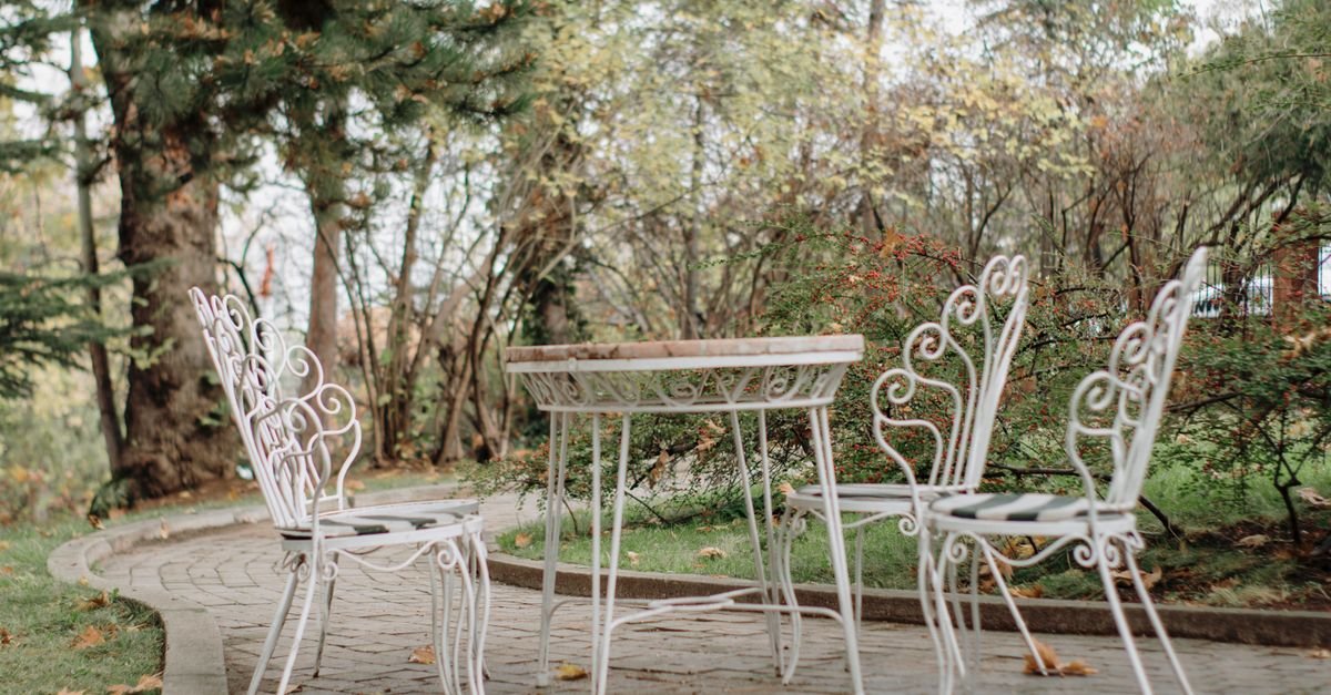 White wrought iron patio table and chairs set on a stone patio