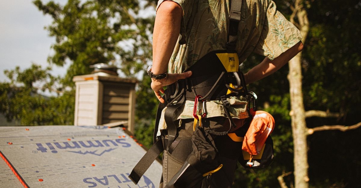 Worker wearing a safety harness on a rooftop, the fall protection required for roof access