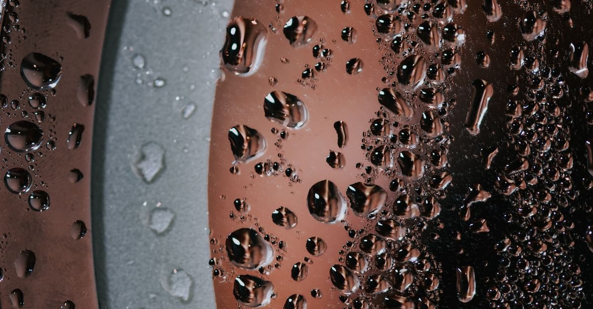 Macro view of water droplets standing on a pane of glass before they evaporate and leave mineral deposits behind