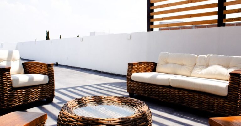 Outdoor wicker furniture set with pale cushions on a sunny terrace
