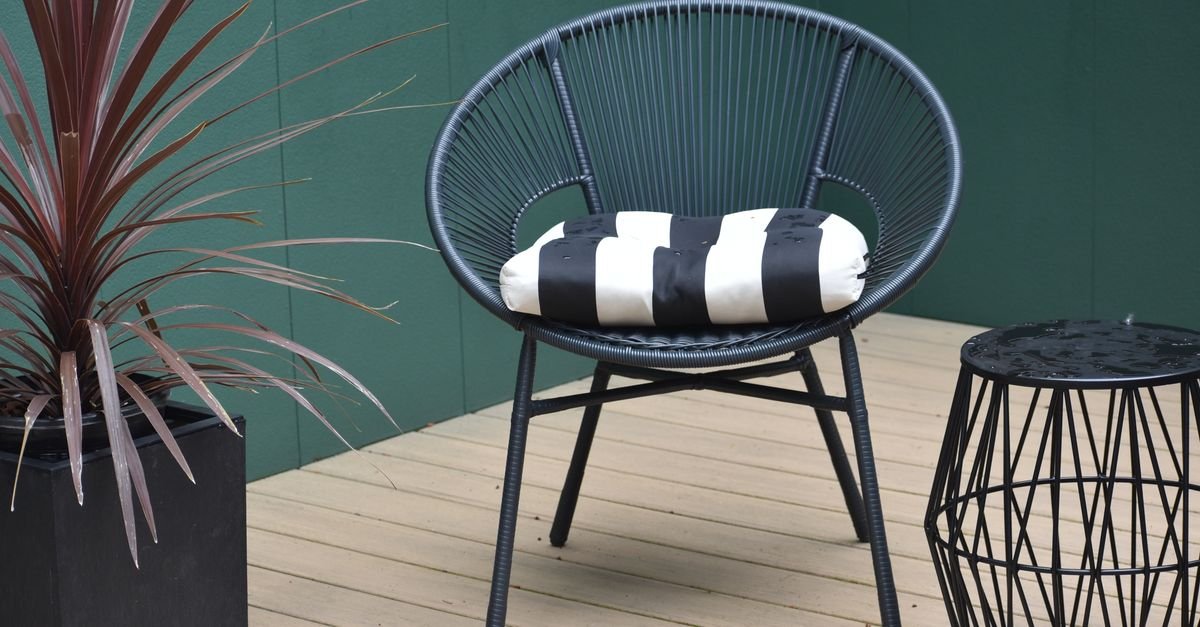 Modern black patio chair with a striped seat cushion on a sunlit terrace