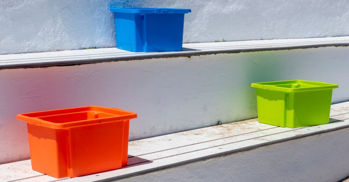 Brightly coloured plastic storage boxes standing on outdoor steps in sunlight