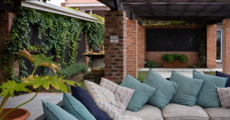 Outdoor patio seating with brightly coloured cushions surrounded by green planting