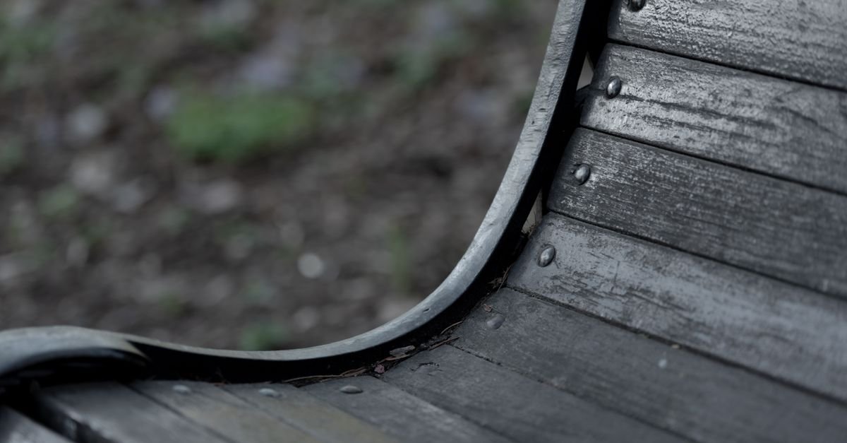 Close-up of a weathered wooden garden bench showing raised grain and open checks in the slats