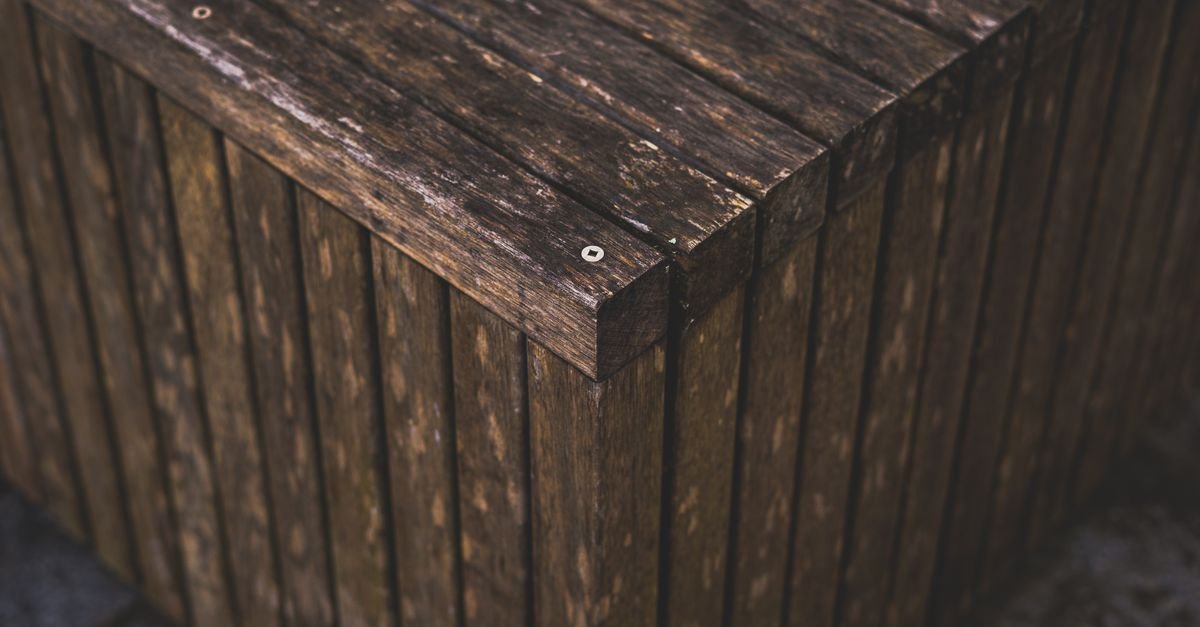 Weathered wooden slats with dark staining spreading out around metal screw heads