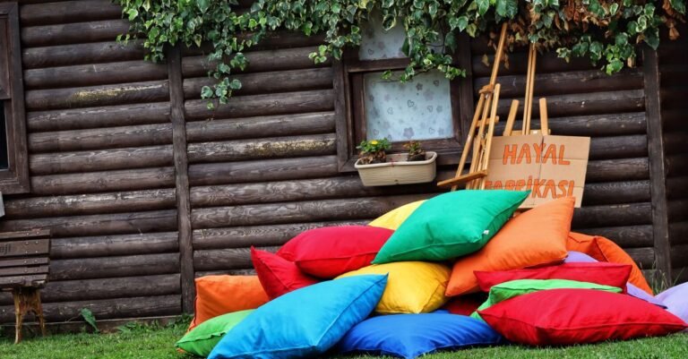 Stacks of bright outdoor cushions piled against the wall of a wooden cabin