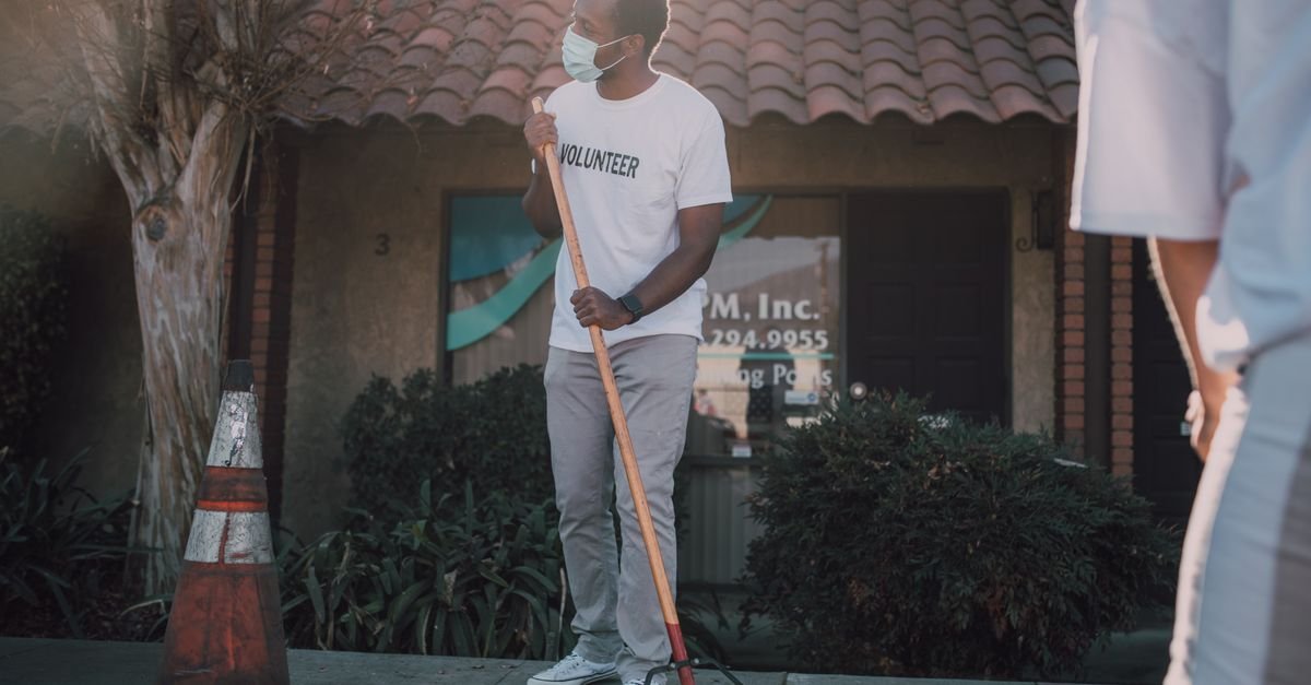 Person sweeping a concrete sidewalk with a push broom before wetting it