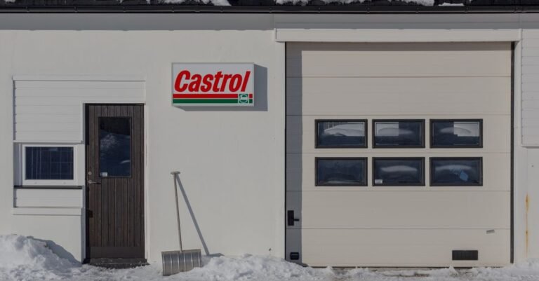 Snow-covered garage exterior with a shovel leaning against the wall in winter