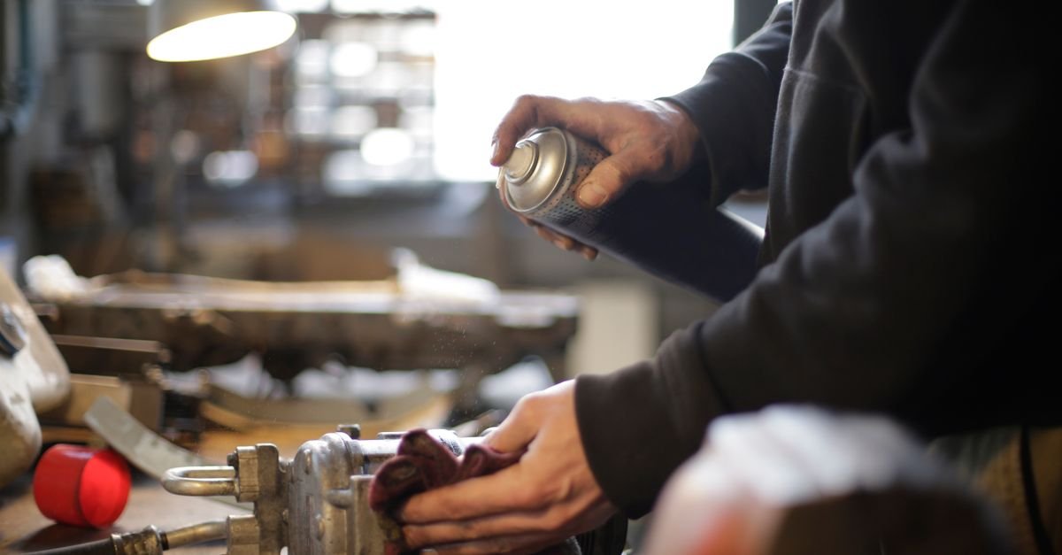Mechanic applying treatment to a metal valve component on a workbench
