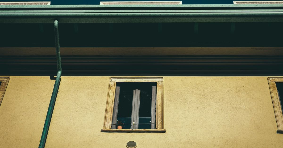 Looking up at the upper storey of an aged building exterior in daylight