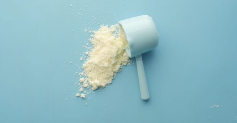 White cleaning powder spilled from a measuring scoop onto a blue surface