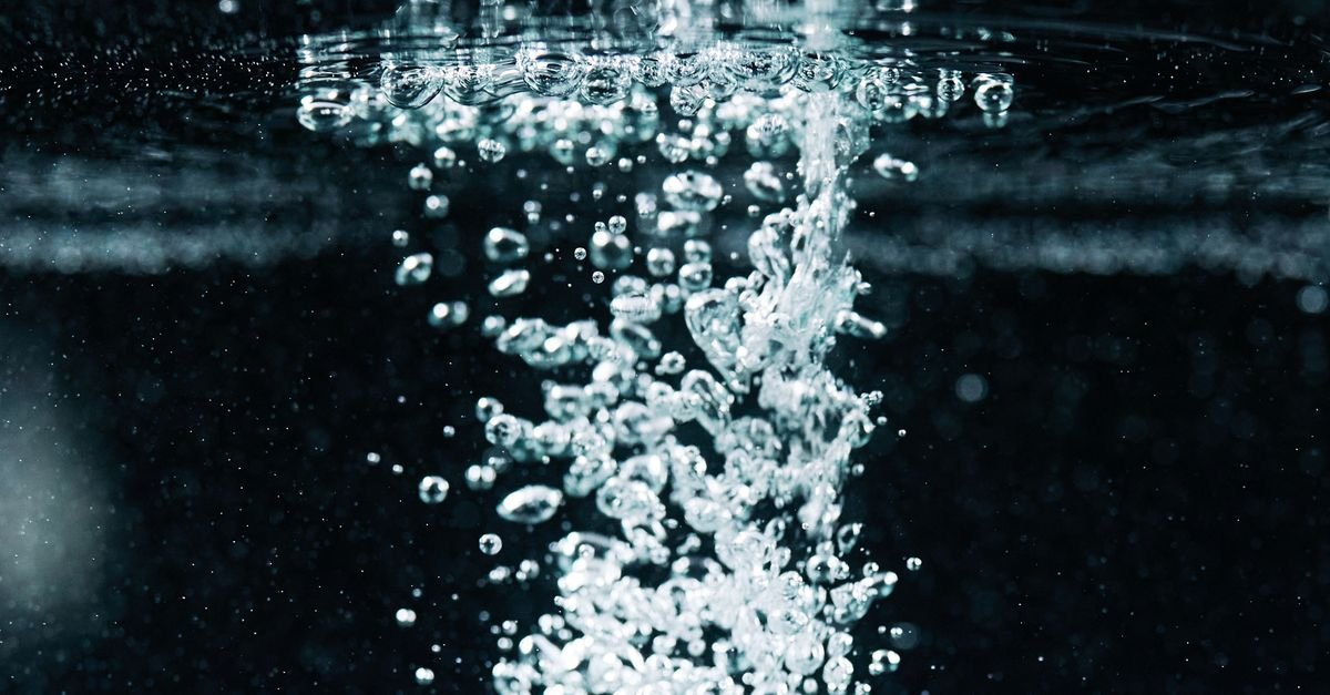 Macro view of fine bubbles rising through water, the oxygen release that gives oxygen bleach its name