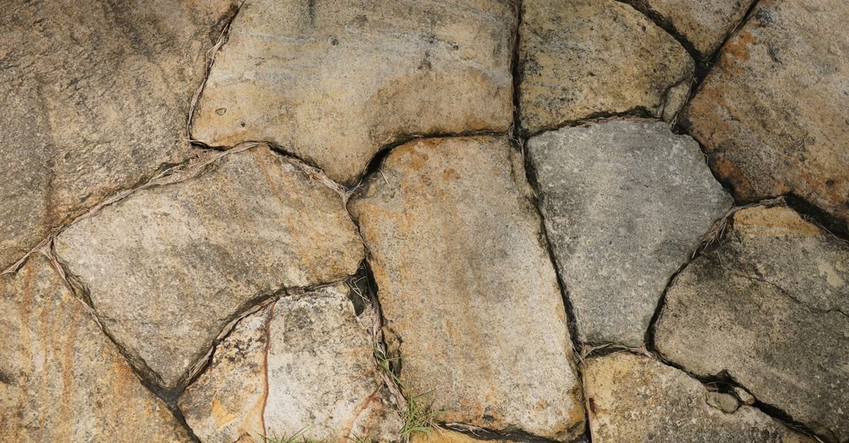 Irregular natural stone slabs in earthy tones laid as patio paving