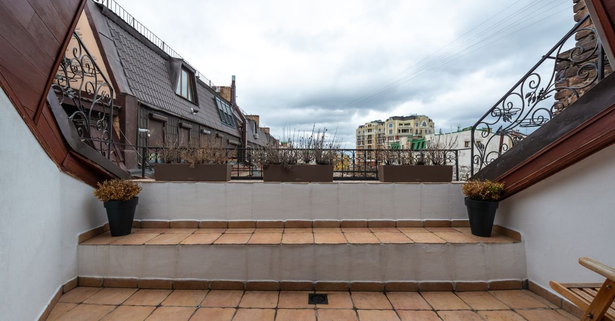 Outdoor terrace with a tiled porcelain floor and a decorative metal railing