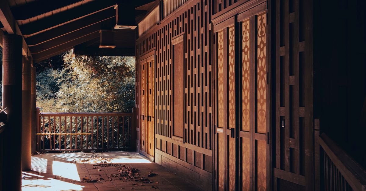 Sunlight and shadow falling across the timber boards of a covered porch floor