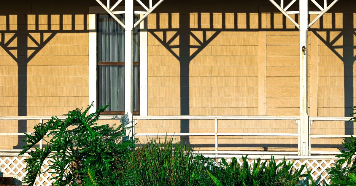 White painted porch railings and balusters against a timber house facade