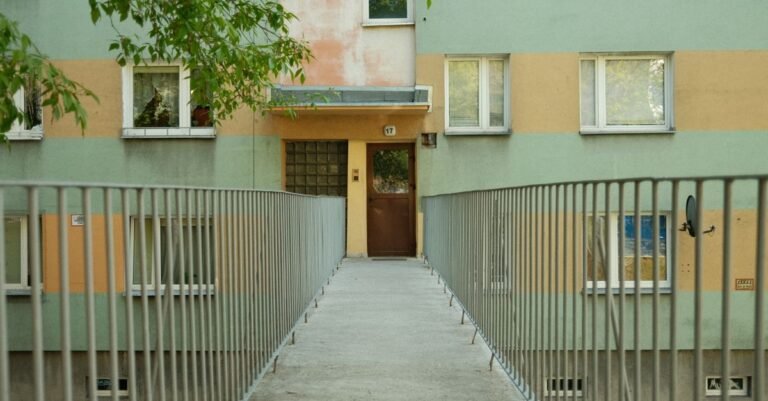 An inviting concrete footpath leading to the front entrance of a residential building on a sunny day