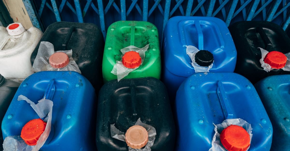 Rows of coloured plastic chemical canisters with red caps viewed from above
