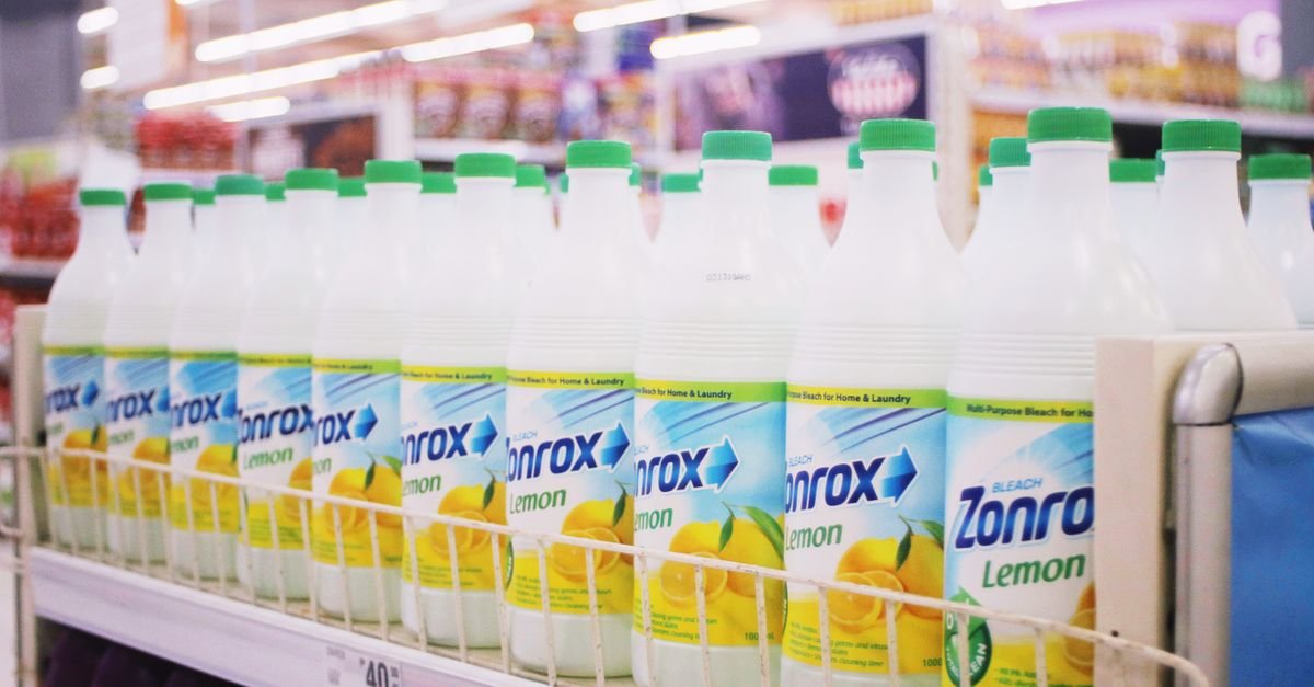Rows of household bleach bottles lined up on a supermarket shelf