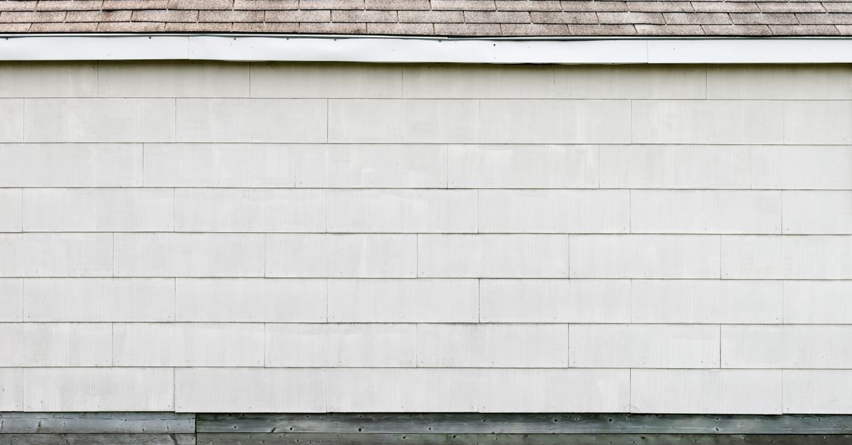 A white lapped siding wall meeting a shingled roof, showing the overlapping horizontal courses