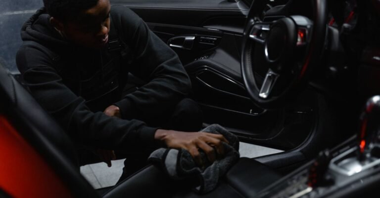 Man wiping a car interior by hand during a detailing clean