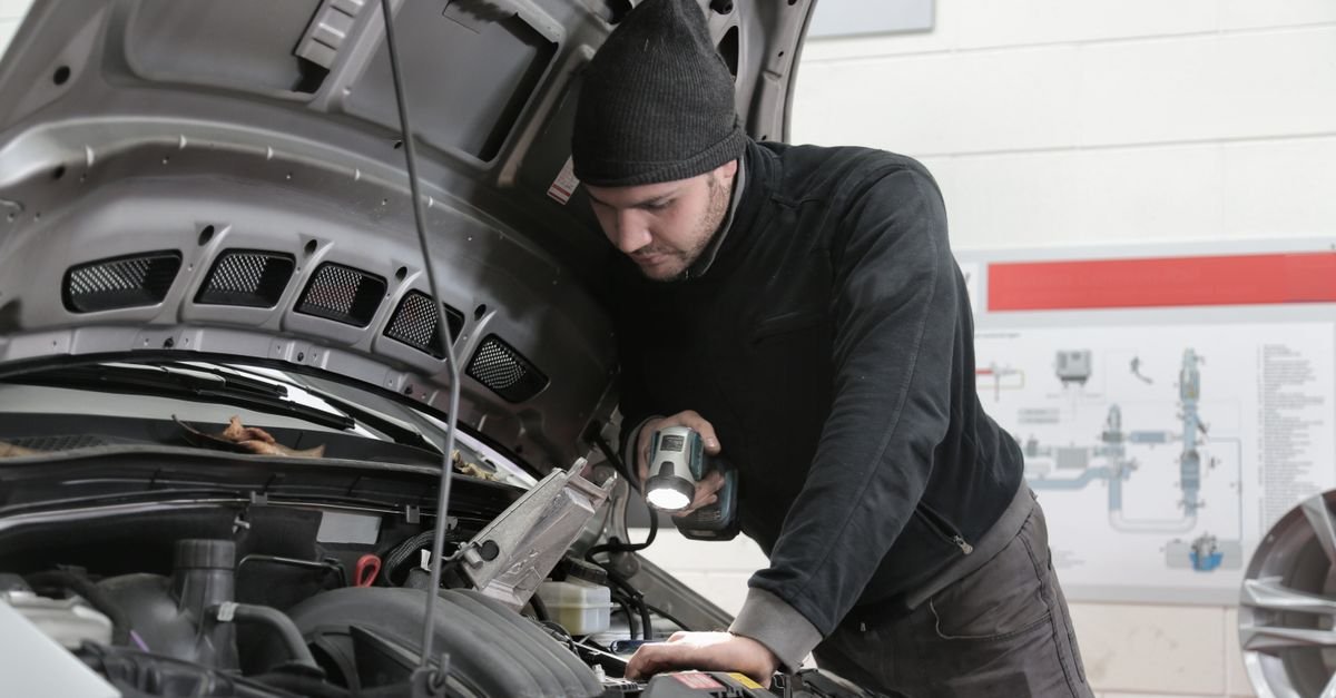 A mechanic inspecting an engine with a flashlight in a garage
