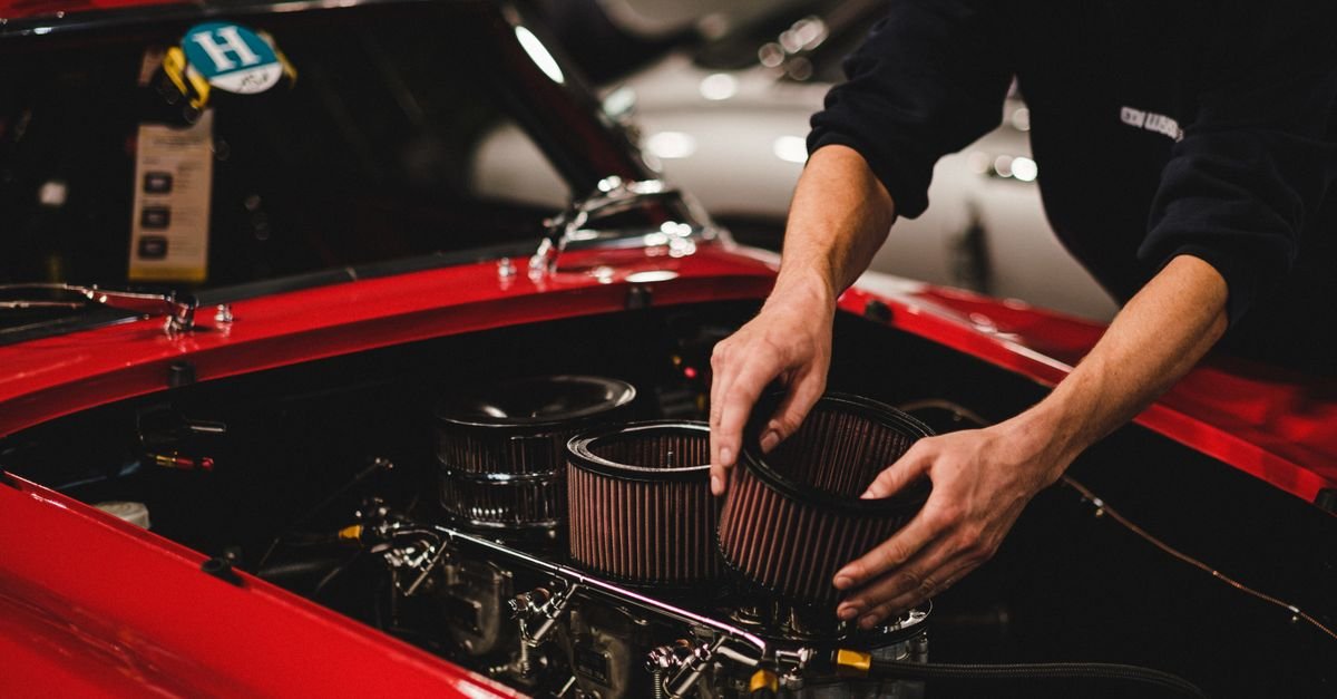 Close-up of a mechanic's hands working on an engine air filter housing
