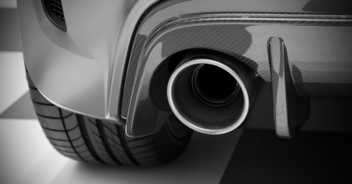 Black and white close-up of a vehicle exhaust outlet, the point a rich engine's unburnt fuel ignites and leaves by