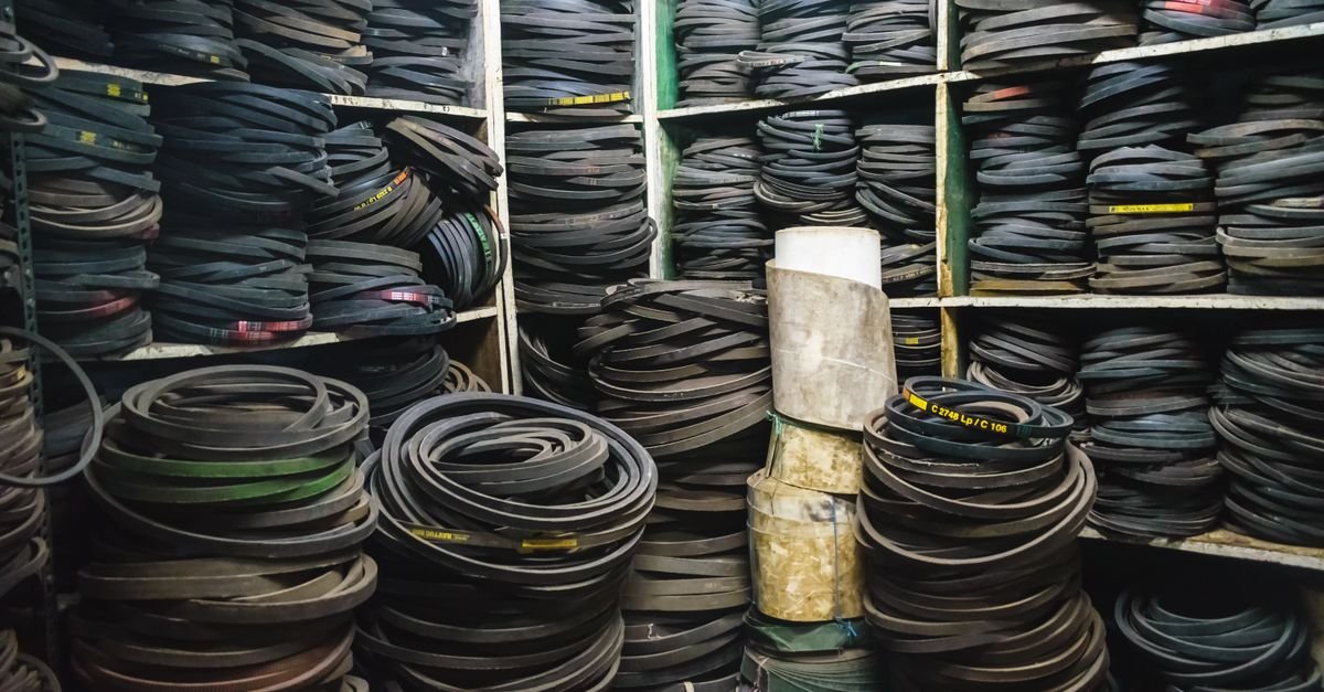 Shelves packed with coiled V-belts of different sections and lengths, each carrying the moulded part number that identifies the exact replacement