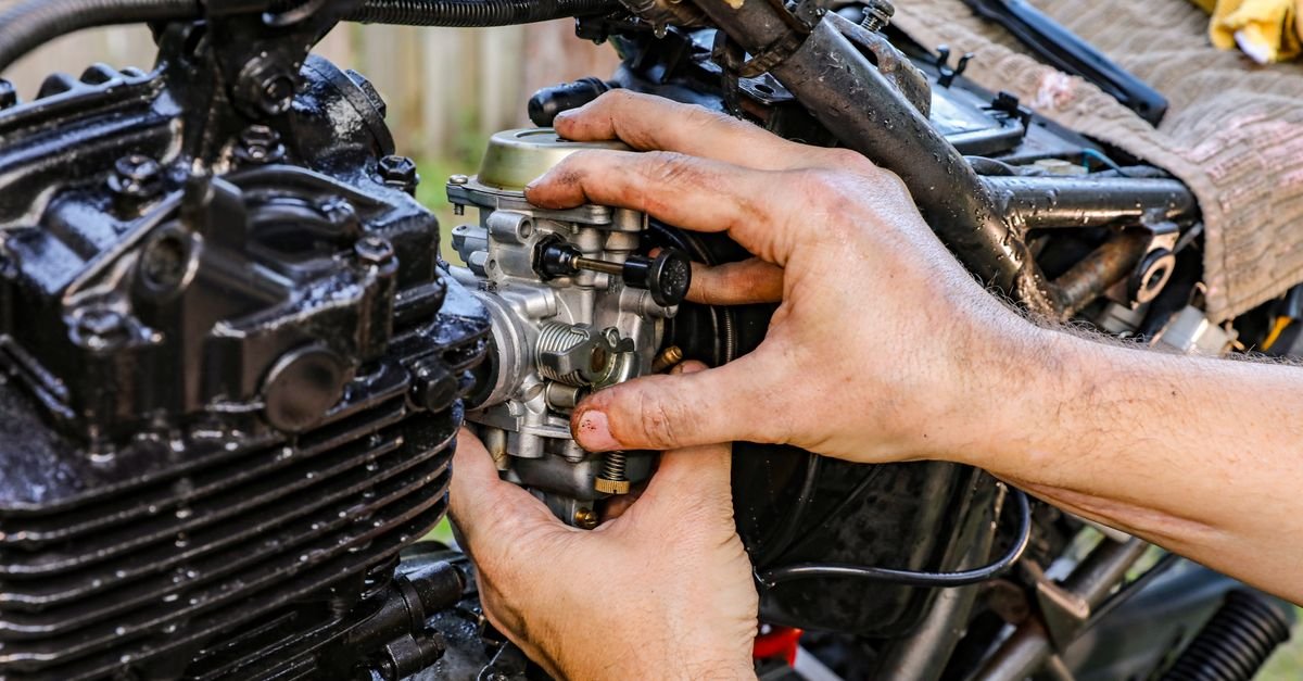 Close-up of a mechanic's hands reassembling a carburetor outdoors