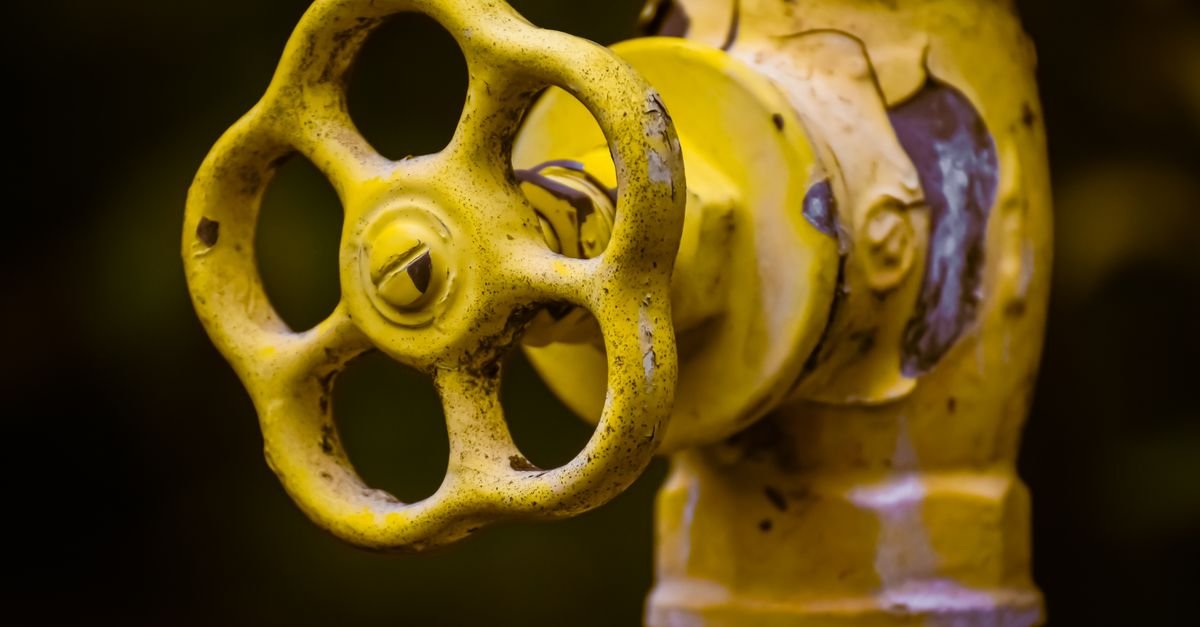 Close-up of a rusty yellow shut-off valve, the sort of partly opened supply tap that quietly starves a pump