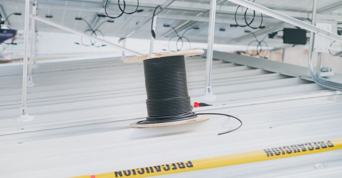 A power cable left tightly coiled beside a rooftop electrical installation instead of run out flat